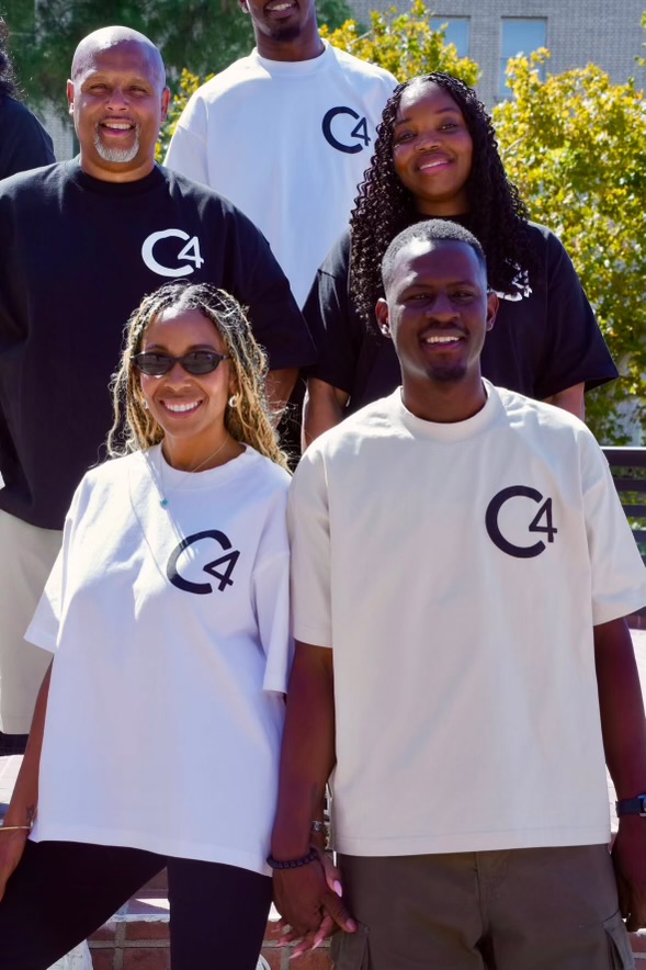 Group smiling in black, white and cream C4 logo tees