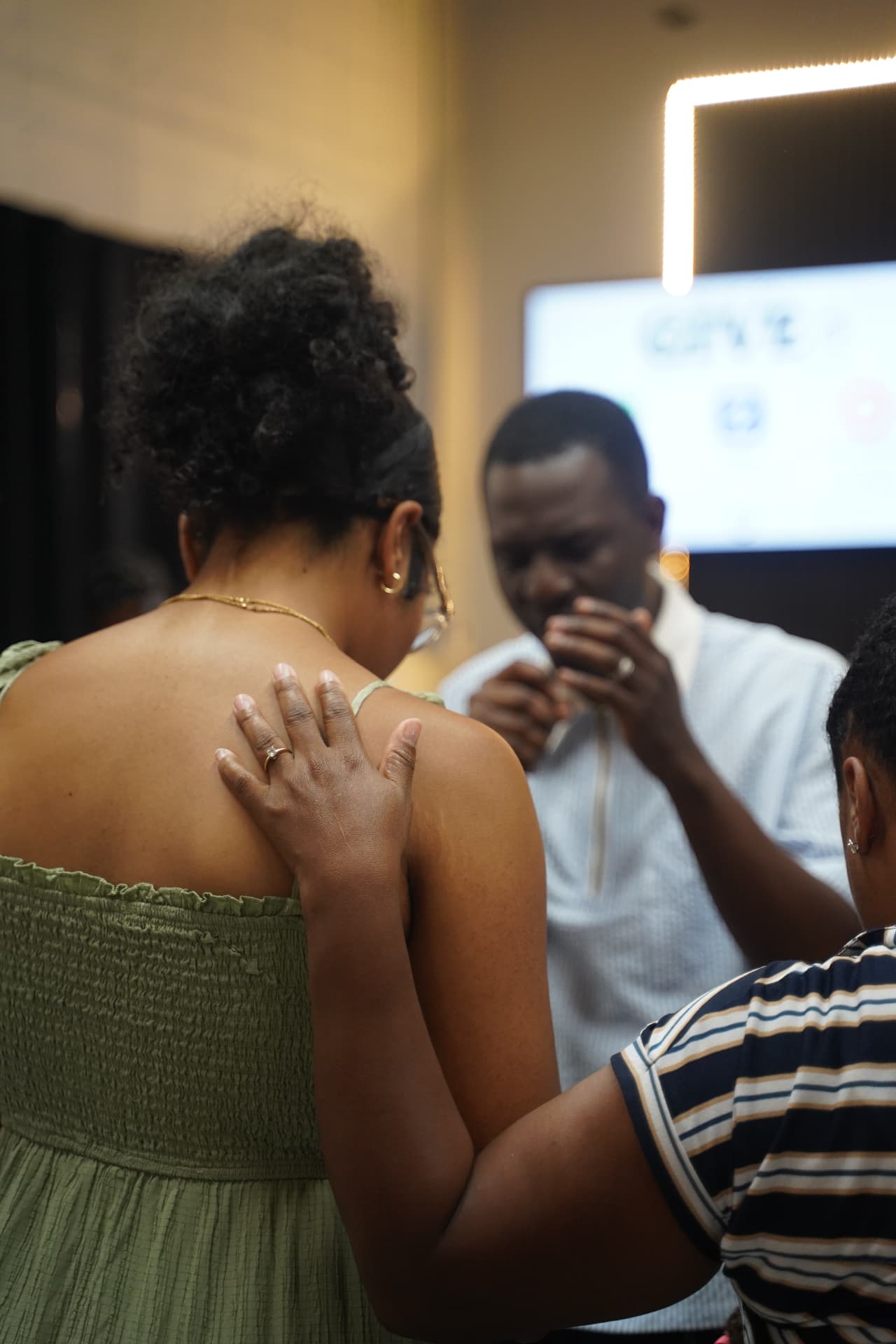 Members of C4 praying together with a hand on a shoulder