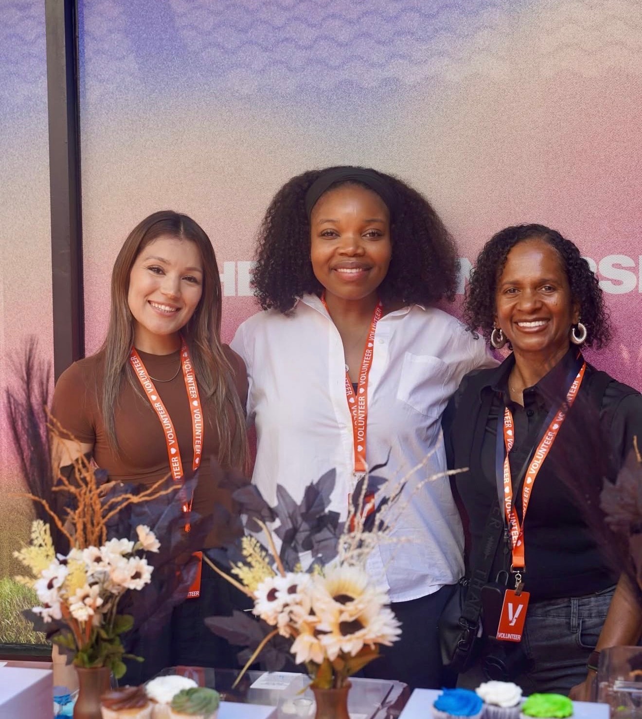Three C4 volunteers smiling behind a welcome table