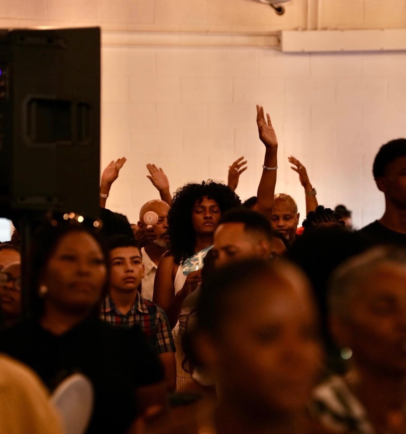 A room full of people worshipping with hands lifted at C4