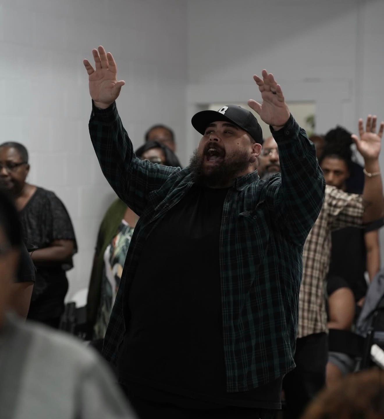 A man singing with both hands raised during worship at C4