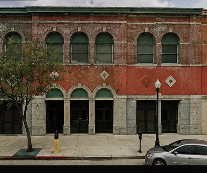 467 W. Fourth Street today — a dormant red brick building with boarded arched windows